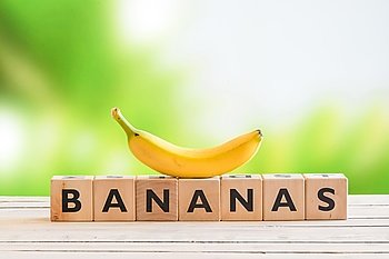Banana sign with a yellow banana on top on a wooden desk