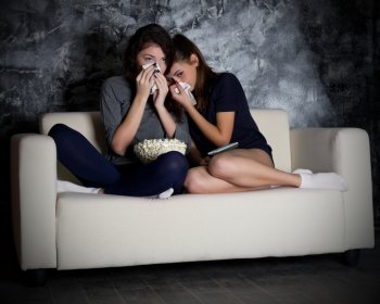 Two crying girls looks TV in dark room