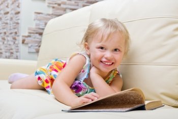 Little girl with book on sofa