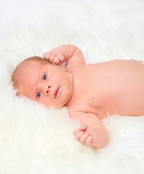 Little baby lying on a fur bedspread