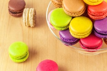 traditional french colorful macarons in a glass cake stand on wooden table