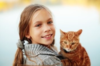 Girl carrying her orange tabby cat