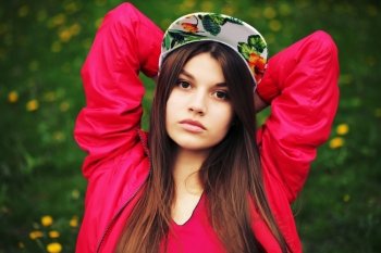 Outdoor fashion portrait of stylish girl. Young brunette woman posing, wearing swag floral cap. Lifestyle portrait bright toned colors.