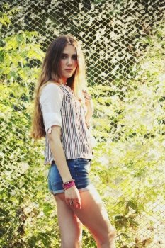 Fashion portrait of beautiful hippie young woman wearing boho chic clothes outdoors. Soft warm vintage color tone. Artsy bohemian style.