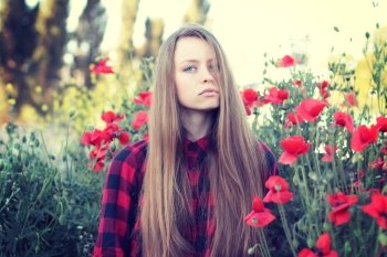 Beautiful young woman in poppy field. Enjoy nature. Photo toned style instagram filters