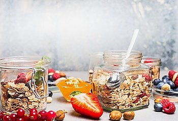 Breakfast in glass jars with muesli, berries, nuts and seeds on light rustic background. Healthy lifestyle and Clean food concept.