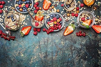 Muesli with fresh berries , nuts and seeds. Balanced breakfast ingredients on rustic background. Muesli breakfast in glass jars, top view, border.  Healthy lifestyle and diet food concept.
