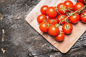 Cherry tomatoes on wooden rustic background, top view, place for text