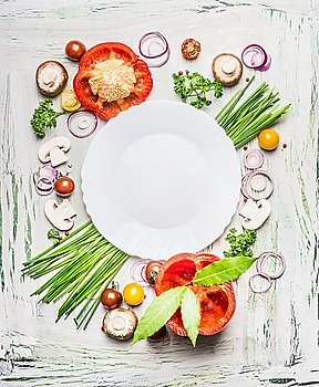Various vegetables and seasoning cooking  ingredients around blank plate on light  rustic wooden background, top view composing. Healthy eating and diet food concept.