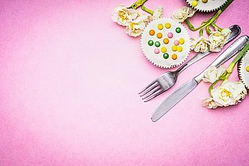Cutlery with beautiful daffodils flowers  and cake on pink background, top view, place for text. Easter food and bake