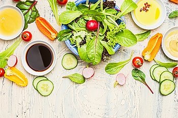 Fresh vegetables salad with various dressing on light rustic background, top view, border. Healthy lifestyle and vegetarian or diet  food concept
