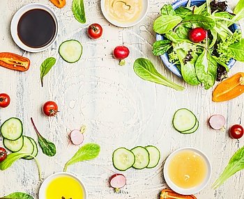 Tasty summer salad and dressing preparation on light rustic background, top view, frame. Healthy lifestyle and vegetarian or diet  food concept