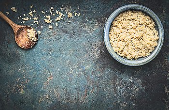Cooked quinoa in blue bowl with cooking wooden spoon on dark rustic background, top view, place for text: recipes and menus, horizontal. Vegan Superfood, healthy eating and nutrition or diet concept.