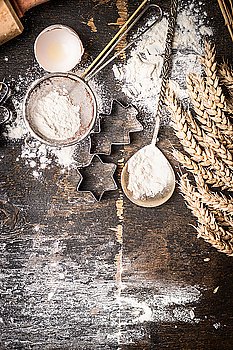 Christmas bake wooden background with star and Christmas tree shaped cookie baking cutter, flour, vintage spoon and ears, top view