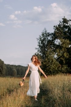 The setting appears to be outdoors with a clear sky and some trees in the background. Its likely a scene from a wedding or a summery outdoor event.. A person standing in a field of tall grass wearing a white dress. 5643