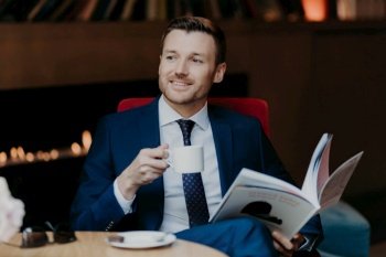 Businessman enjoying coffee while reading a magazine in a cozy interior.