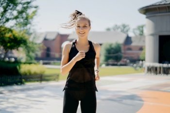 Confident young woman jogging in urban park, fitness in the city
