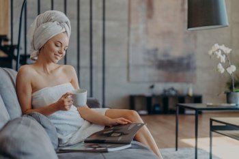 Relaxed woman in towel enjoys coffee while reading in a cozy home
