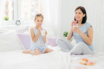 Mother and daughter enjoying milkshakes in a bright bedroom setting