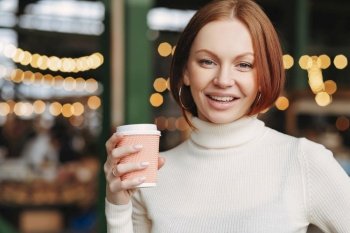 Smiling woman with coffee cup in urban cafe