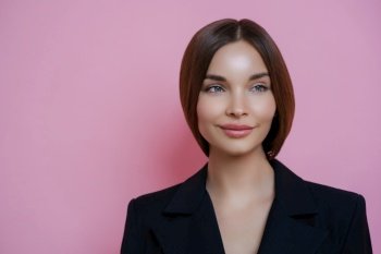 Sophisticated young woman with sleek hair in a navy blazer, poised and stylish, against a pink background