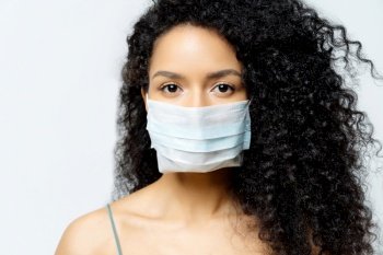 Woman with curly hair in a medical mask, white background