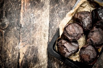 Chocolate fresh muffins . On a wooden background.. Chocolate fresh muffins .