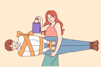 Woman holds man wrapped in gift ribbon as metaphor for romantic valentine day or relationship anniversary gift. Girl with smile shows shopping bag and boyfriend to advertise sale for valentine day. Woman holds man wrapped in gift ribbon as metaphor for romantic valentine day gift