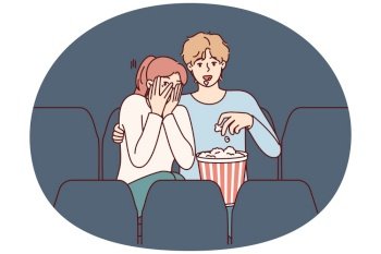 Guy and girl are watching horror movie in cinema and eating popcorn enjoying films about vampires. Fearful woman closes eyes with hands sitting in cinema near man watching horror movie with interest. Guy and girl are watching horror movie in cinema and eating popcorn enjoying films about vampires