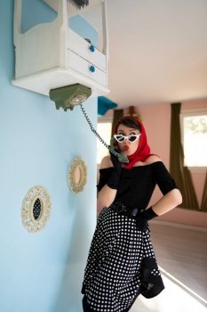 a girl retro style, speaks by phone, in an upside-down house, as well as furniture placed on the up