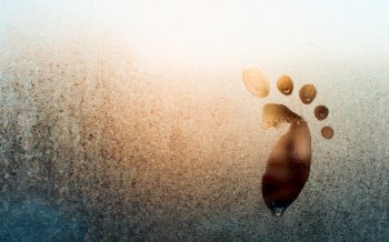 Drawing of child’s foot on frozen window, copy space. Frosty pattern on glass. Funny creative concept. Solar flare