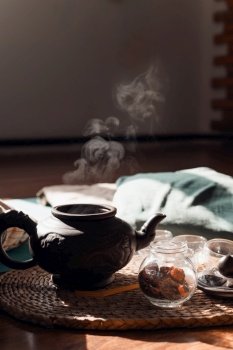 Herbal tea ceremony at sunrise. Clay teapot, glass cups on a tray. Hot tea raises steam in the light of the sun. Concept of harmony, relaxation, pacification