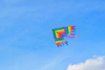 Rainbow kite flying high in blue sky, viewed from below. Symbol of freedom, rainbow, happiness, children’s toy.. Rainbow kite flying high in blue sky, viewed from below. Symbol of freedom, rainbow, happiness, children’s toy