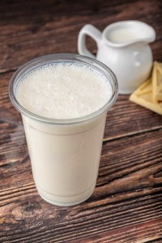 White Chocolate milk in take away glass on wooden table