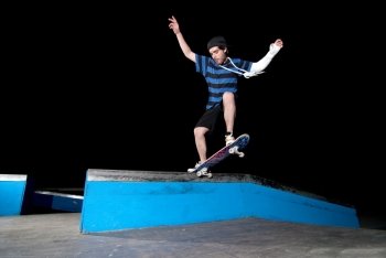 Skateboarder on a slide at night at the local skatepark.