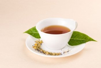 Red tea in white ceramic cup with green leaf decoration.