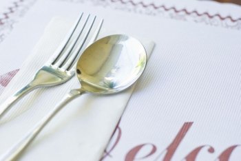 Fork, spoon and napkin on dinner table.