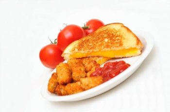 Grilled cheddar cheese sandwich with tater tots and ketsup, whole tomatoes in the background and isolated on white.. Grilled Cheese And Fries