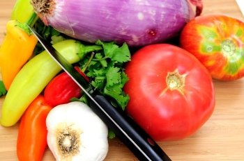Tomatoes, red onion, garlic, cilantro with red and green chilies on a wooden cutting board ready to cut for fresh salsa.. Vegetables For Salsa
