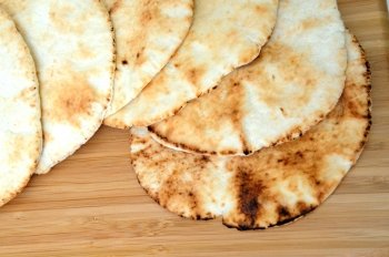 Six middle eastern flat bread disks stacked on top of each other.. Pita Bread