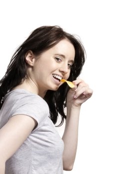 young woman eating potato chip. young woman from side eating potato chip with a smile