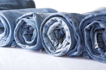 roll blue denim jeans arranged in line, isolated on white