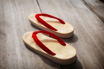 A pair of Japanese sandals on a wooden floor.