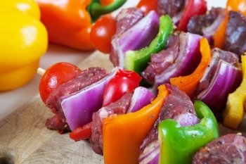 Three freshly prepared beef shish-ka-bob with vegetables, marinated and ready for the grill.   Shallow depth of field.