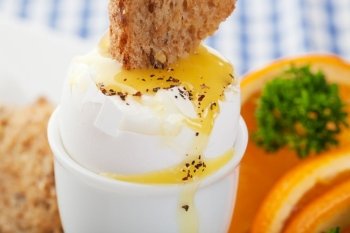 Toast dipped into the warm, runny, yolk of a soft boiled egg.