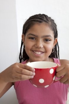 Little girl with a large cup of tea and a happy smile 