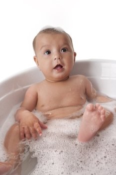 Baby girl sitting in a bathtub with foam