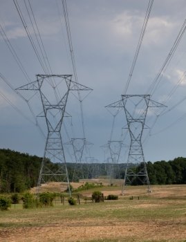 Large metal electricity pylons march across the countryside
