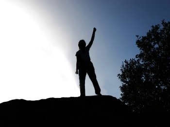 Backlit of a person by lifting the arm as a sign of victory