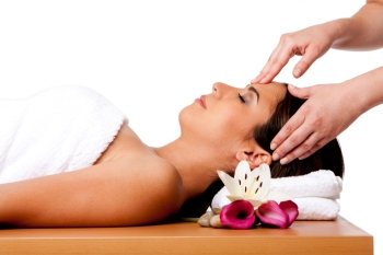 Beautiful happy peaceful sleeping woman at a spa, laying on wooden massage table with head on pillow wearing a towel getting a facial massage, isolated.